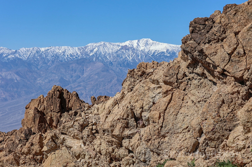 A view of the jagged ridge near the end of the trail, with a snow capped ridge seen in the distance, fading into the blue sky above.