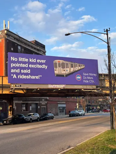 A billboard shows a graphic of a train with the text, "No little kid ever pointed excitedly and said 'A rideshare!'" The billboard promotes Chicago Transit Authority (CTA) services, with smaller text stating, "Save Money. Do More. Ride CTA." The background includes a blue sky with clouds and urban buildings.